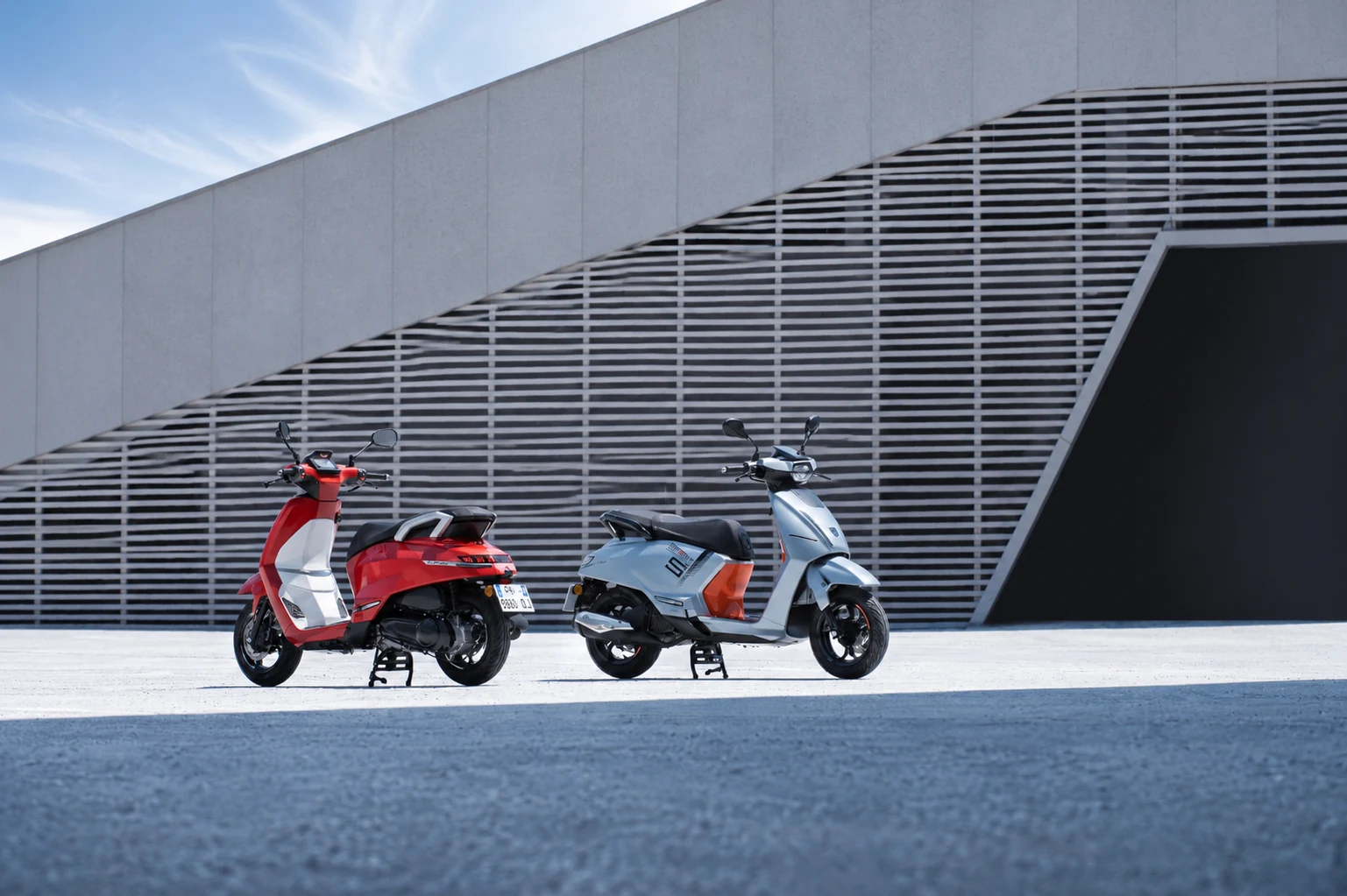 Django Evo Active Cherry Red dan Sport Silver di antara garis arsitektur.